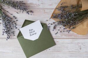 Paper card note with text RELAX REFRESH RECHARGE from green envelope. Lavender flower. Top view, flat lay. Concept of mental spiritual health self care wellbeing mindfulness photo