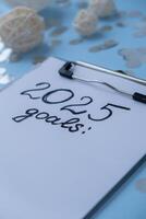 2025 GOALS New year's resolutions on paper note with Christmas decor. Making promises for new year, setting goals. Creating dream vision board motivation photo