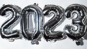 Happy new year 2023 metallic balloons on white background. Greeting card silver foil balloons numbers Christmas holiday concept. Celebration party congratulation decoration photo