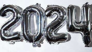 Happy new year 2024 metallic balloons on white background. Greeting card silver foil balloons numbers Christmas holiday concept. Celebration party congratulation decoration photo
