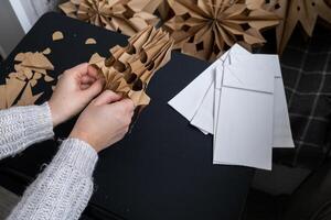 Master class of making craft paper snowflakes for conscientious Christmas decor. Sustainable celebration minimal responsible DIY holiday project. Step by step instruction photo