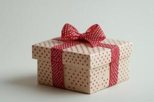 Closed dotted gift box with red ribbon bow is waiting to be opened photo