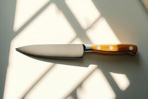 Large sharp kitchen knife lying on white table with window shadows photo