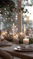 Christmas table setting decorated with burning candles, greenery and string lights photo