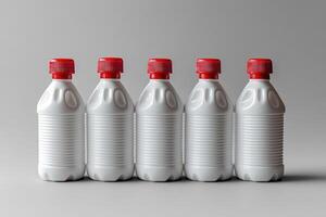 Row of white plastic bottles with red caps standing on gray background photo
