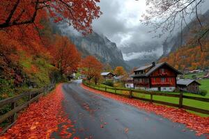 Wet asphalt road covered with red leaves leading to swiss chalets in autumn photo