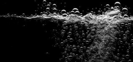 Soda water bubbles splashing underwater against black background. photo