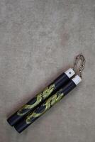 Vertical photography of training nunchucks for self training in use of melee weapons on light background, traditional oriental edged weapons of impact and strangulation type photo