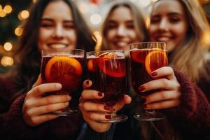 Group of young friends drinking mulled wine with orange at christmas market, festive background, bokeh, lights photo