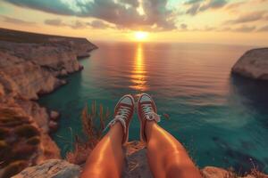 young traveler watching a beautiful sunset in the sea on a rock, rear view photo