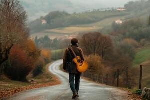 a man with a guitar case on his back walks along a picturesque road, rear view photo