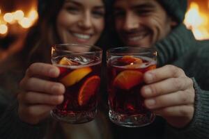 Couple with glasses of delicious mulled wine close-up by the fireplace photo