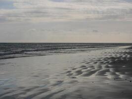 Seashore in sunlight with reflections on wet sand photo