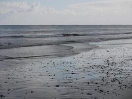 Seashore in sunlight with reflections on wet sand photo