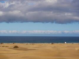 Sandy beach in Maspalomas, Gran Canaria at dusk with cloudy sky. Seascape background wallpaper with copy space photo