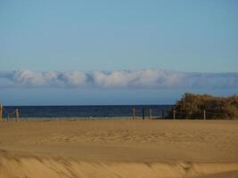 Sandy beach in Maspalomas, Gran Canaria at dusk with cloudy sky. Seascape background wallpaper with copy space photo