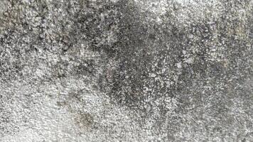 Close-up of a rough, weathered concrete wall with a mottled, uneven texture. photo