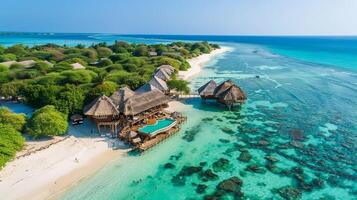 Aerial view of a tropical island resort with a swimming pool, thatched roof bungalows, white sandy beach, and turquoise water. photo