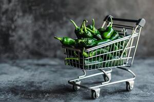 A miniature shopping cart filled with fresh green chili peppers. photo