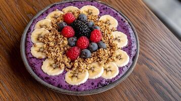 A bowl of blueberry smoothie with bananas, raspberries and granola photo