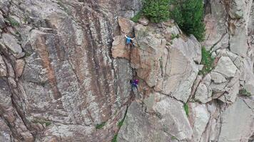 Climbers ascending steep cliff face working together video