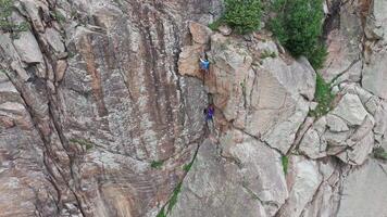 Two climbers are making their way up a steep rock face video