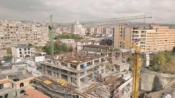 Aerial static view construction site with crane cary block material and workers working on site. Real estate property business in kantron district. Yerevan capital investments concept video