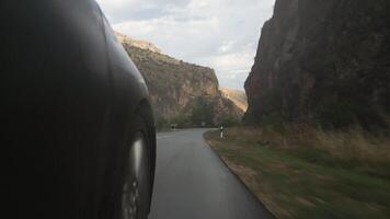 Close tilt up view Driving car front wheel POV point of view, close-up wheel spinning on countryside in empty asphalt road in autumn mountains video