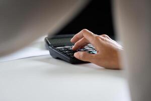 Focused Businesswoman Using Calculator for Financial Analysis in Modern Office Setting photo