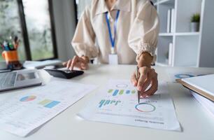 Focused businesswomen Analyzing Financial Data with Calculator in Modern Office Setting photo