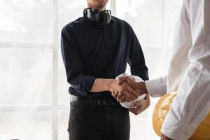 Engineers Shaking Hands in Agreement at Construction Site with Safety Gear and Blueprints photo