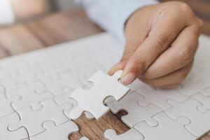 Hand push last piece jigsawto finish success planning concept solve puzzle, logical thinking, Concept of challenge and determination as the person works to complete the puzzle. photo