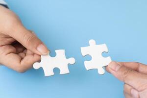 Business team holding parts of jigsaw puzzle trying to find solution to problem together. Concept of challenge and determination as the person works to complete the puzzle. photo