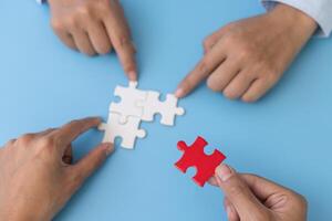 Business team holding parts of jigsaw puzzle trying to find solution to problem together. Concept of challenge and determination as the person works to complete the puzzle. photo