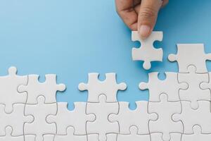 Hand push last piece jigsawto finish success planning concept solve puzzle, logical thinking, Concept of challenge and determination as the person works to complete the puzzle. photo
