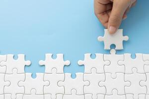 Hand push last piece jigsawto finish success planning concept solve puzzle, logical thinking, Concept of challenge and determination as the person works to complete the puzzle. photo