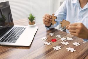 Business team holding parts of jigsaw puzzle trying to find solution to problem together. Concept of challenge and determination as the person works to complete the puzzle. photo