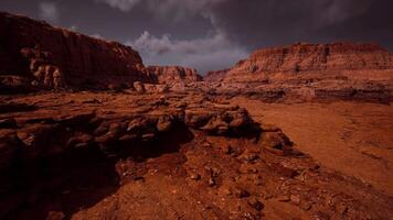 Stark reddish landscape with rugged rock formations under dark clouds in desert video