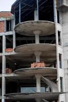 An unfinished concrete building structure symbolizes urban development challenges and opportunities, with stacks of bricks awaiting construction completion photo