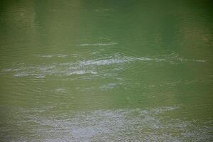 Calm green water surface with gentle ripples, illustrating tranquility and nature, perfect for Earth Day related themes photo