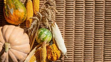 Autumn harvest theme with assorted pumpkins, corn, and wheat on a wicker background, celebrating Thanksgiving and abundance photo