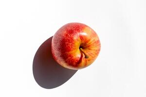 A vibrant red apple casting a shadow on a white background, symbolizing healthy eating and the concept of freshness photo