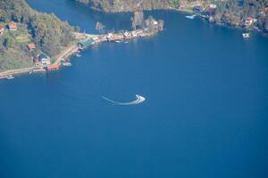Aerial view of a speedboat making waves on a serene lake surrounded by lush greenery, perfect for a summer vacation concept photo