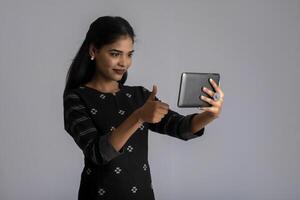 Young Indian girl using a mobile phone or smartphone on gray background photo