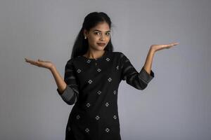 Beautiful girl holding and presenting something in the hand with a happy smiling face. photo