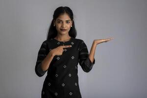 Beautiful girl holding and presenting something in the hand with a happy smiling face. photo