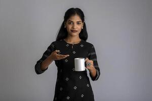 pretty young girl with a cup of tea or coffee posing on grey background photo
