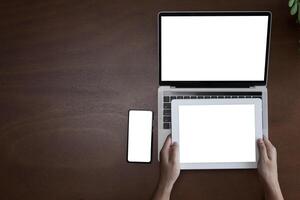 View on a dark table. Female hands using a laptop, smartphone and holding a tablet, modern technology devices that are popular today. photo