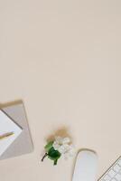 Workspace with a computer, white flowers and stationery on a pastel beige background. Distance work, online learning concept with place for text. photo