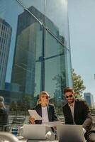 Business colleagues working with documents sitting outside of office on cafe terrace photo
